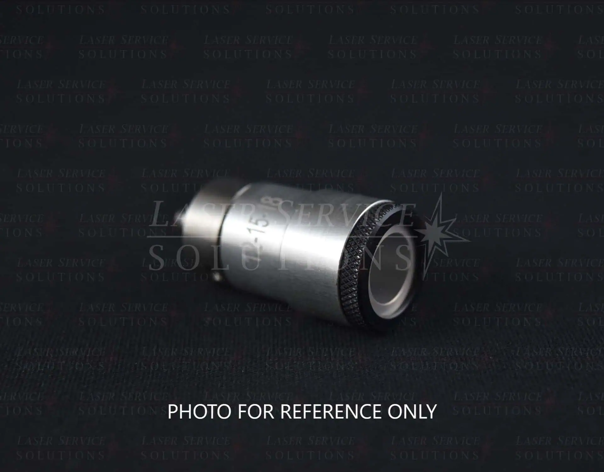 A Candela Gmax Pro Optics Cap Lens Kit, featuring a metal cylindrical design with black and silver sections, lies on a dark surface. PHOTO FOR REFERENCE ONLY is written at the bottom.