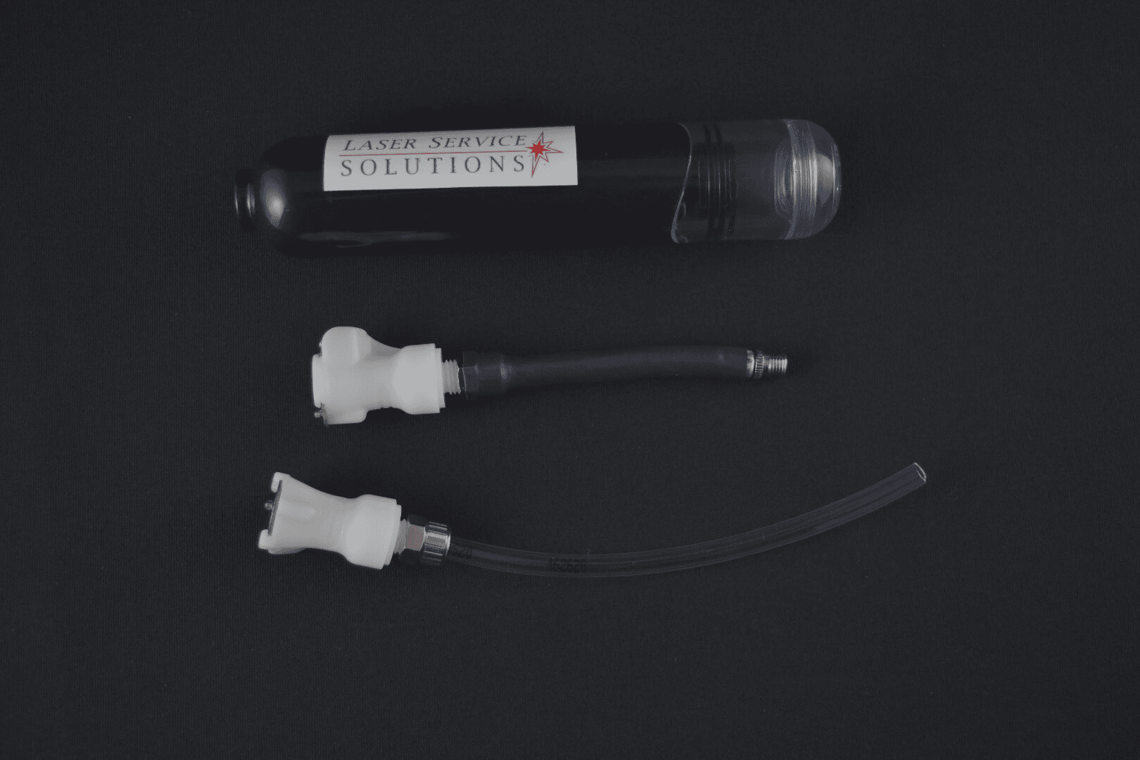 A Handpiece Drain Pump Kit, featuring a black canister labeled Laser Service Solutions and two white plastic connectors with attached hoses, is displayed on a black background.