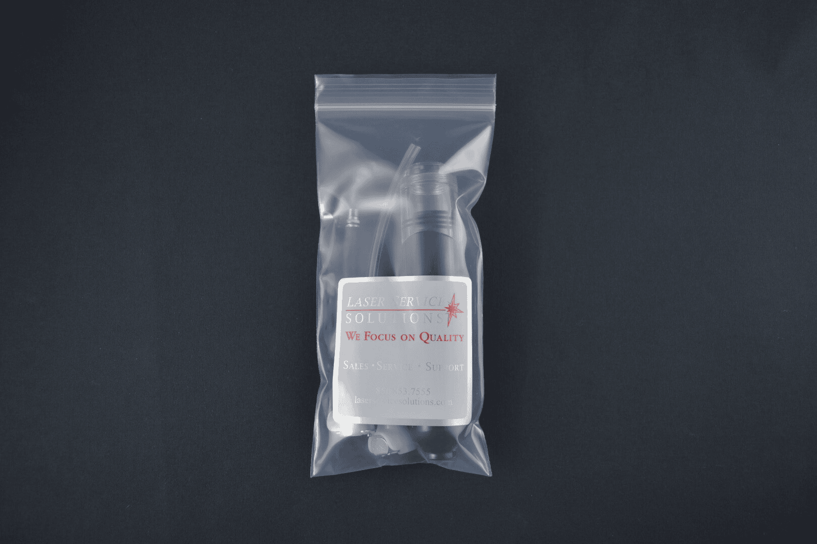 A Handpiece Drain Pump Kit, featuring a small labeled bottle and dropper inside a clear plastic bag, is displayed on a dark, plain background.