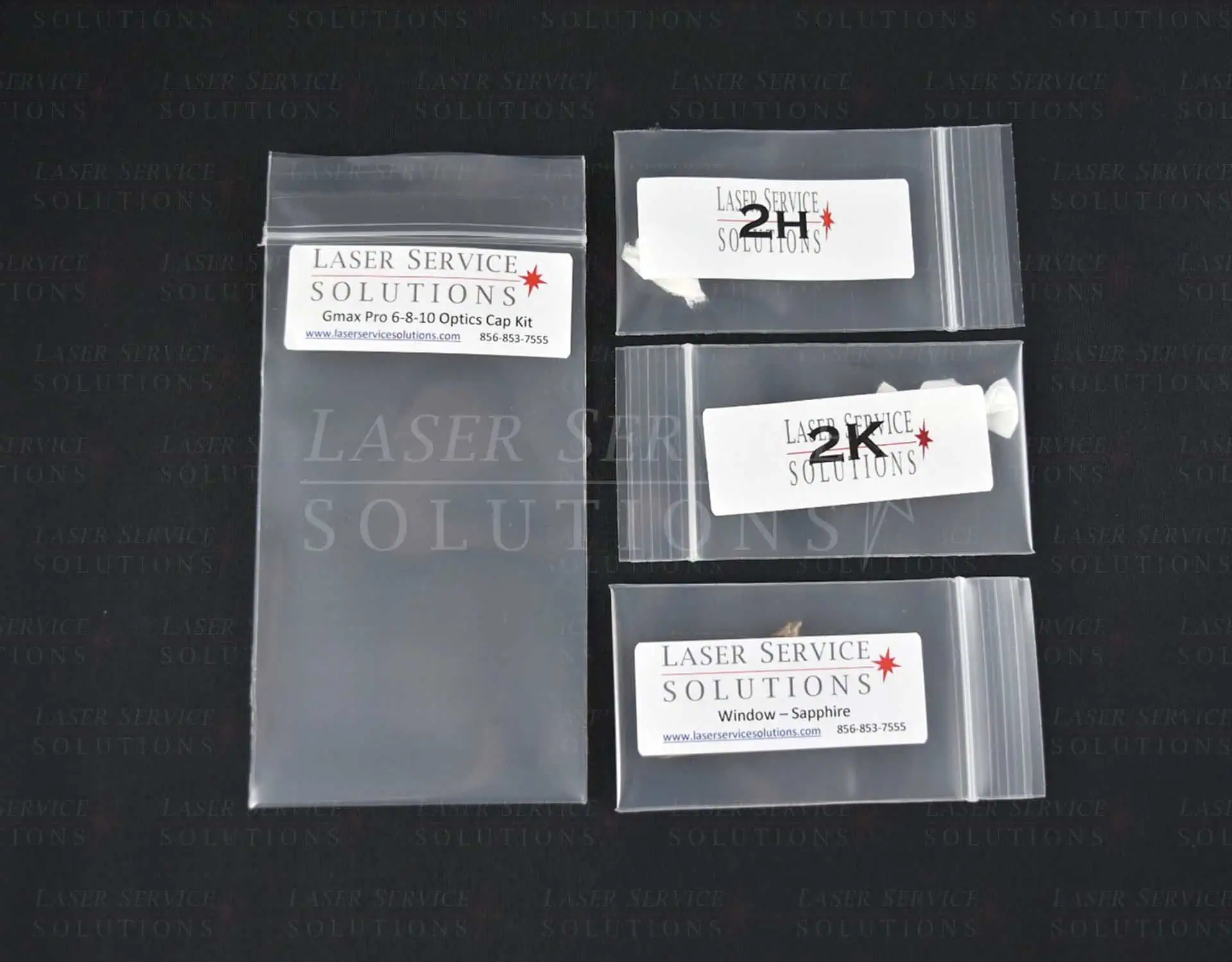 Four clear plastic bags with Laser Service Solutions labels, each designated for a different Candela Gmax Pro Optics Cap Lens Kit, are displayed on a dark background. The largest bag is empty, while the other three are smaller and sealed.