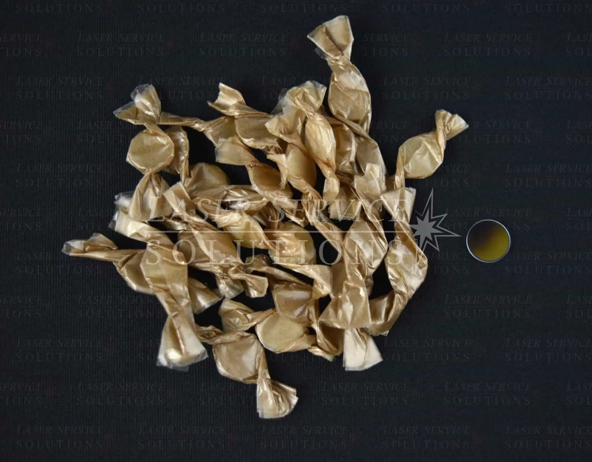 A pile of Cutera Handpiece Windows wrappers is spread out on a dark surface, with a small yellow circular object nearby.