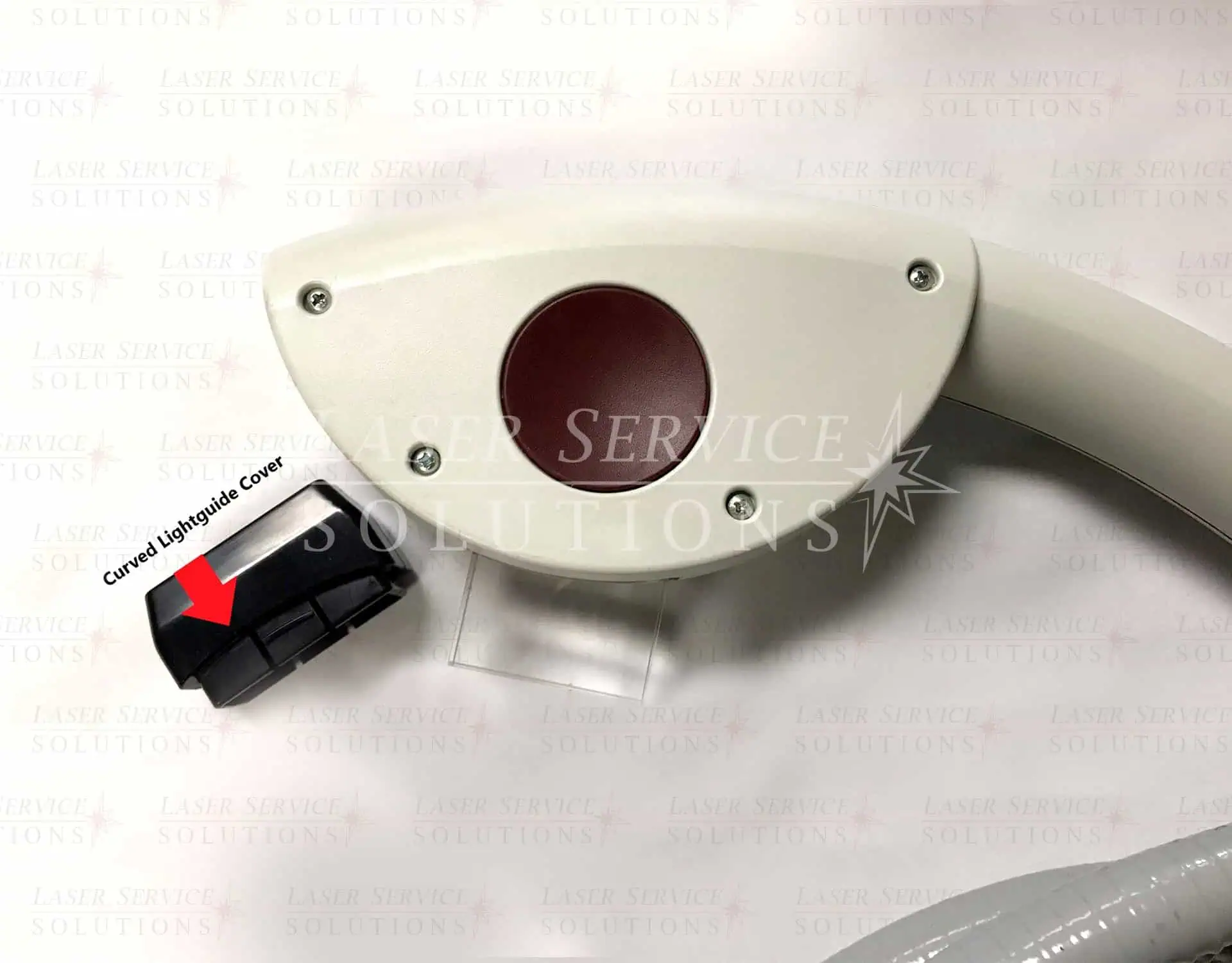 Close-up of a curved laser device with a red circular lens, labeled Harmony Lightguide Cover, with a red arrow pointing to a black attachment on the left side. The background features faint Laser Service Solutions text.