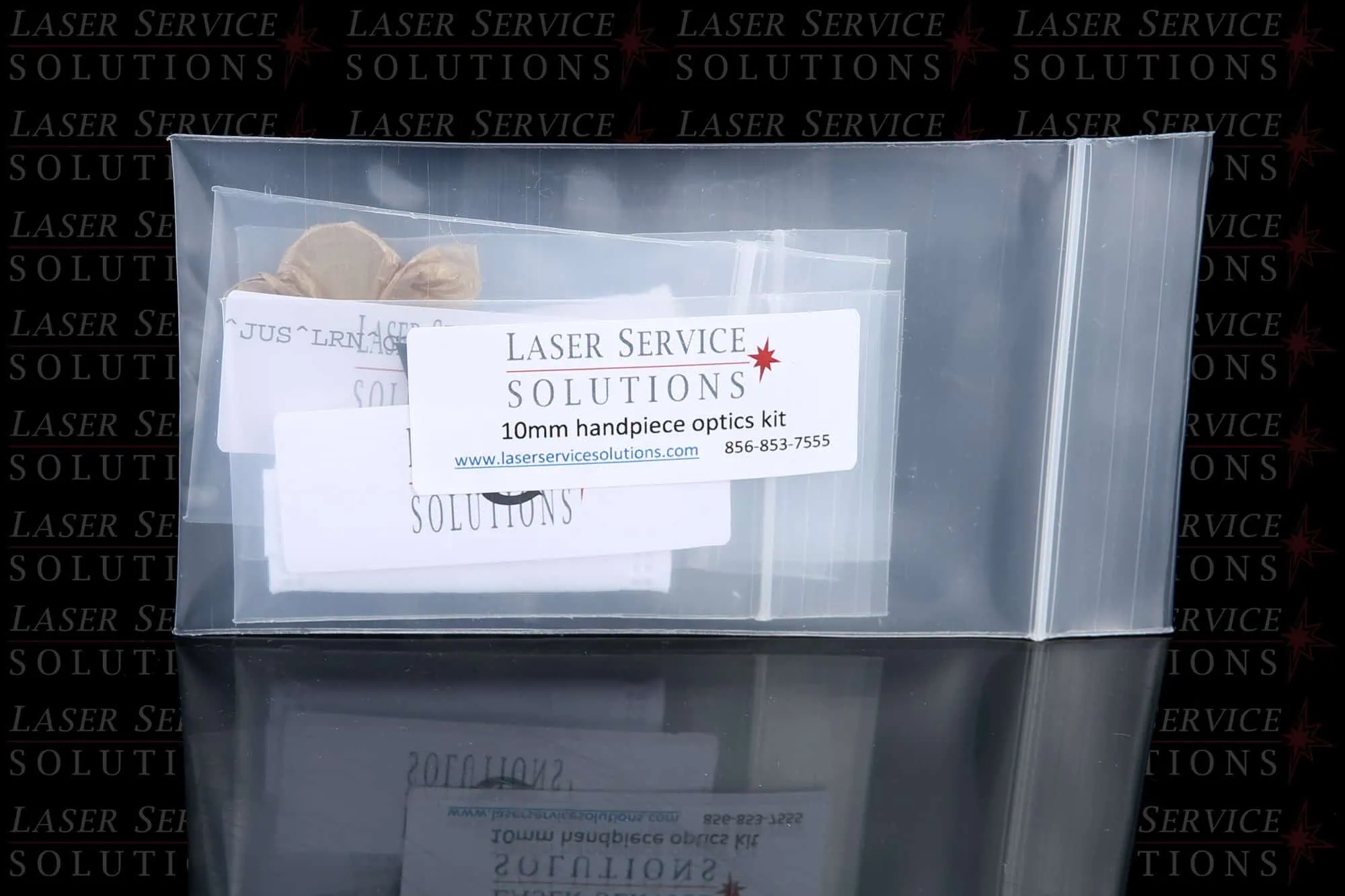 A clear plastic bag labeled “Elite Handpiece Optics Kit” containing small items, with the Laser Service Solutions logo and contact information visible on the label.