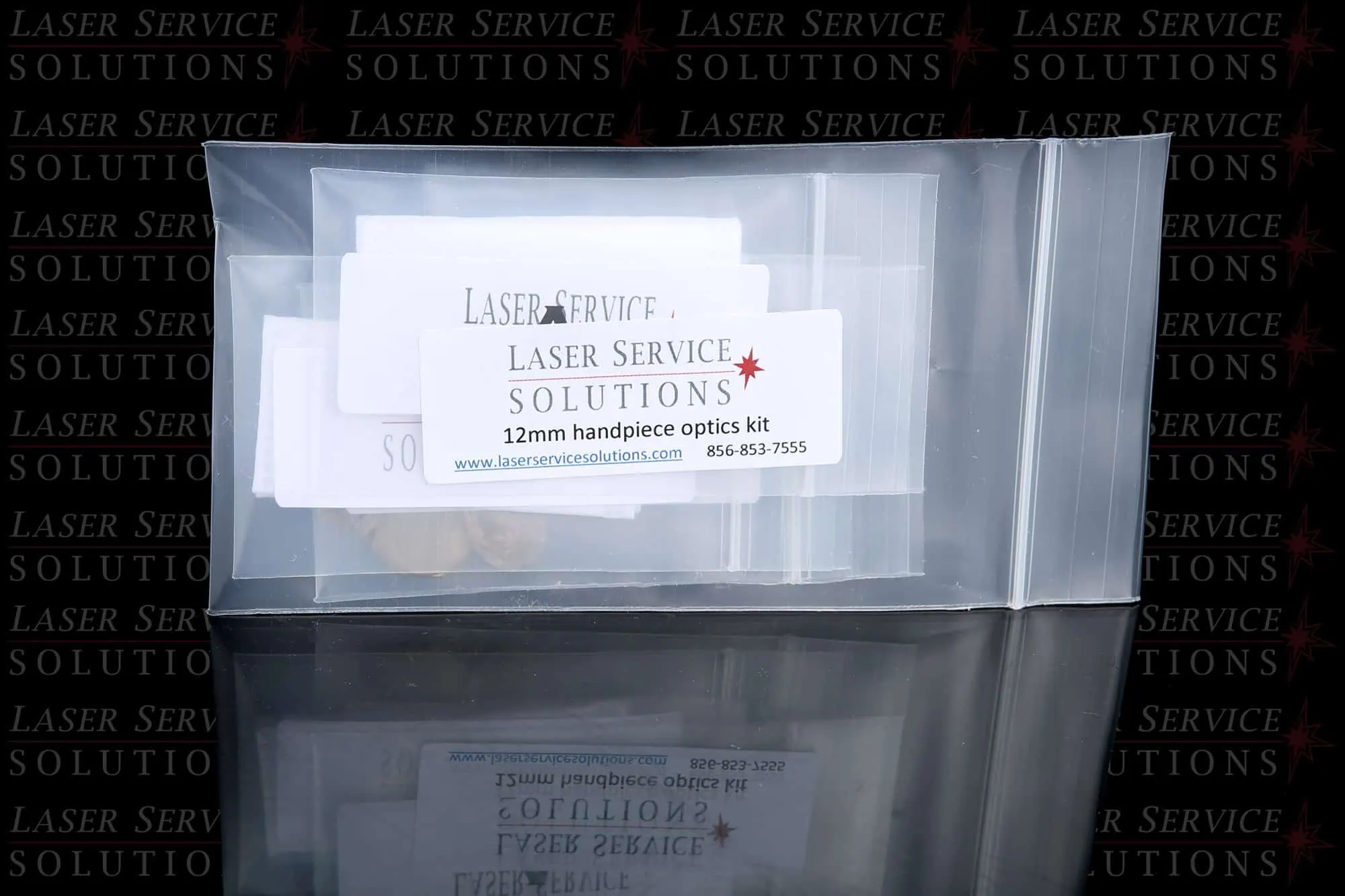 A clear plastic bag containing an Elite Handpiece Optics Kit from Laser Service Solutions, with a business card visible through the bag. The background features a repeated Laser Service Solutions logo.