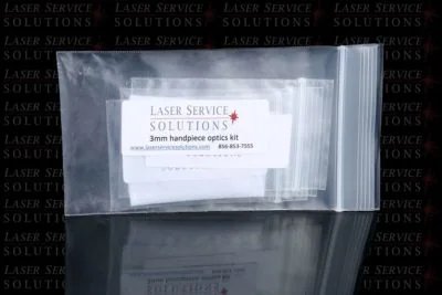 A clear ziplock bag labeled Laser Service Solutions Elite+ Handpiece Optics Kit, featuring a website and phone number, displayed on a reflective surface with the company logo in the background.