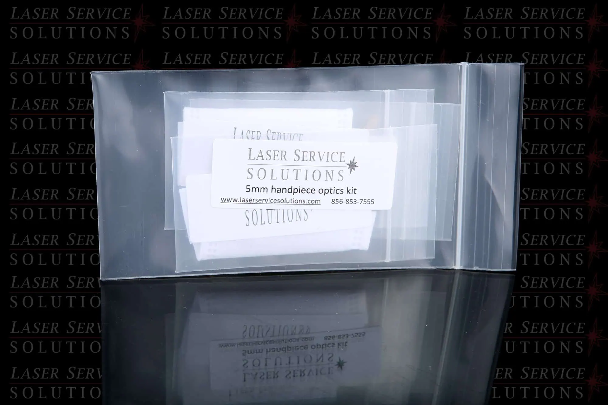 A clear plastic bag containing an Elite MPX Optics Kit card labeled Laser Service Solutions, with contact information. The background features a repeating Laser Service Solutions logo pattern.