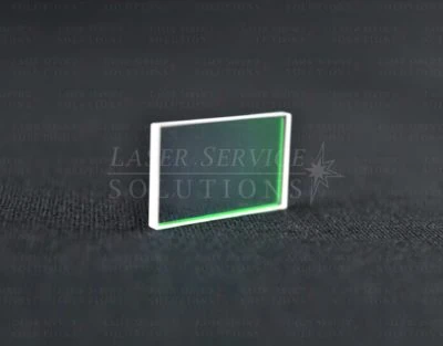 An Elite MPX Yag Turning Mirror, featuring a rectangular and transparent design with a subtle green edge, rests atop a textured dark surface. In the background, the partially visible Laser Service Solutions logo can be seen.