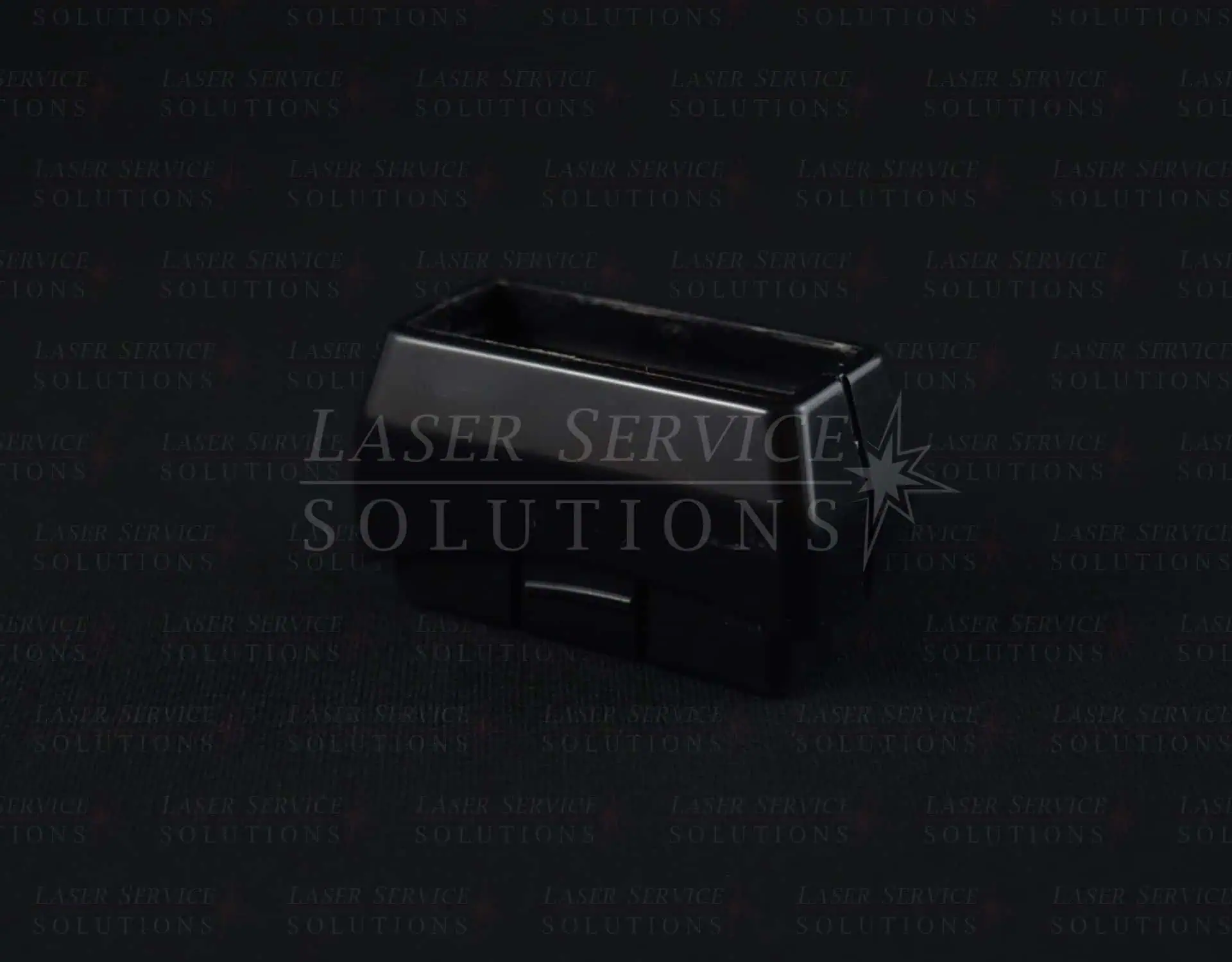 A Harmony Lightguide Cover—a small black plastic rectangular box with an open top—is photographed against a dark background.