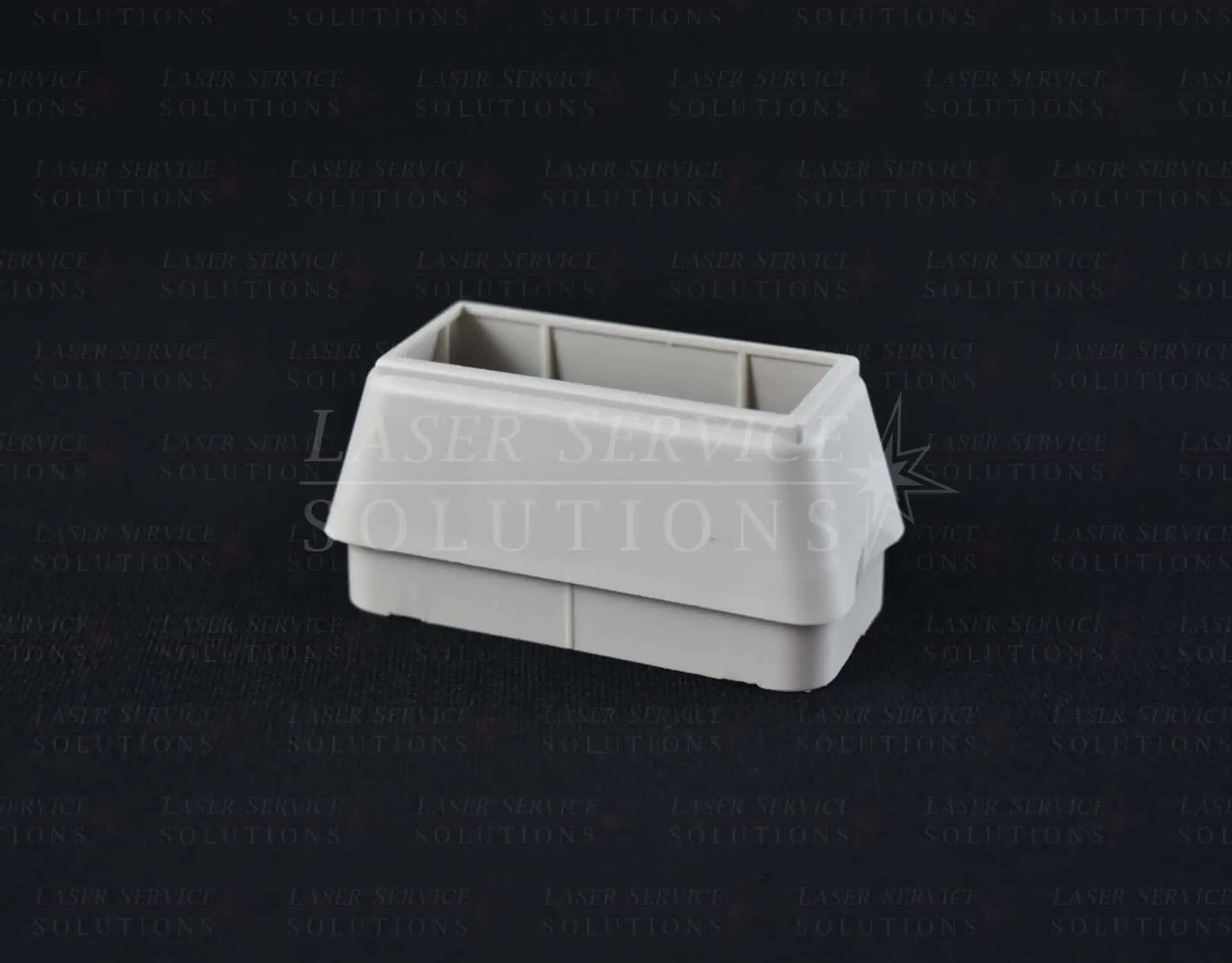 A Harmony Lightguide Cover, a gray plastic rectangular container with an open top and interior compartments, is placed on a dark surface.
