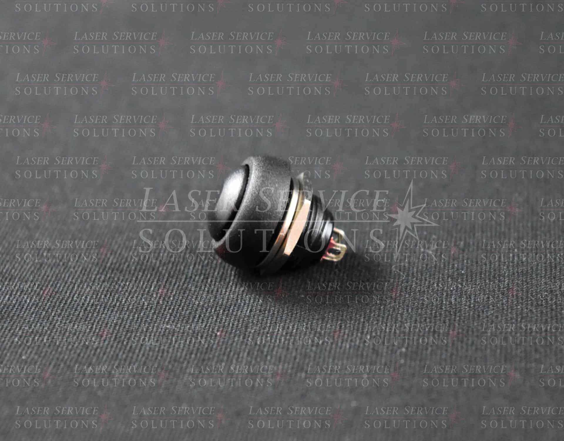 Soprano XL Trigger Button: black plastic push button with metal threading and two prongs, shown resting on a textured dark surface. The background features a subtle, repeated “Laser Service Solutions” watermark.