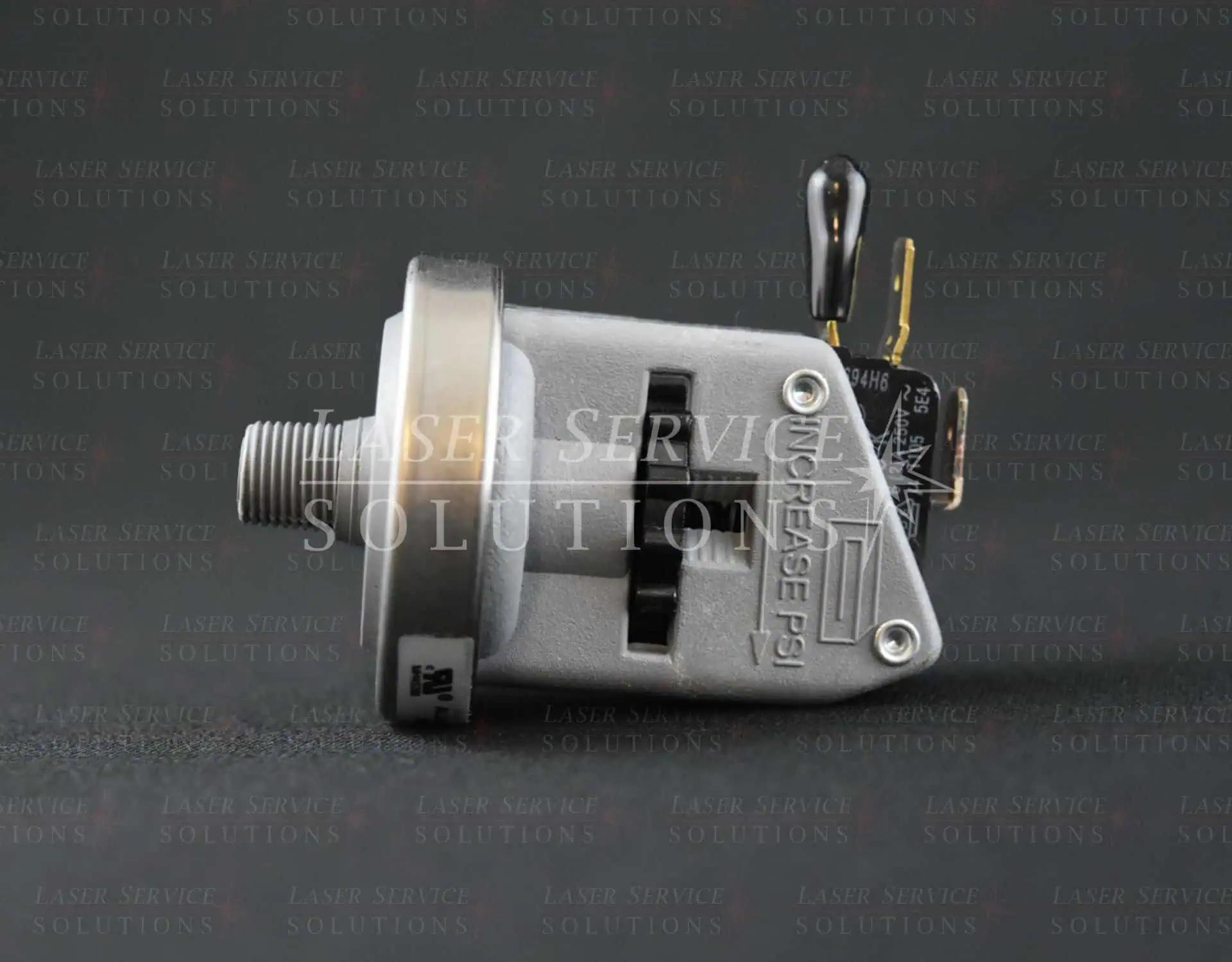 A close-up side view of a Candela Vbeam Perfecta Dye Pressure Switch with a metallic finish and electrical connector, set against a dark background with faint text reading Laser Service Solutions.