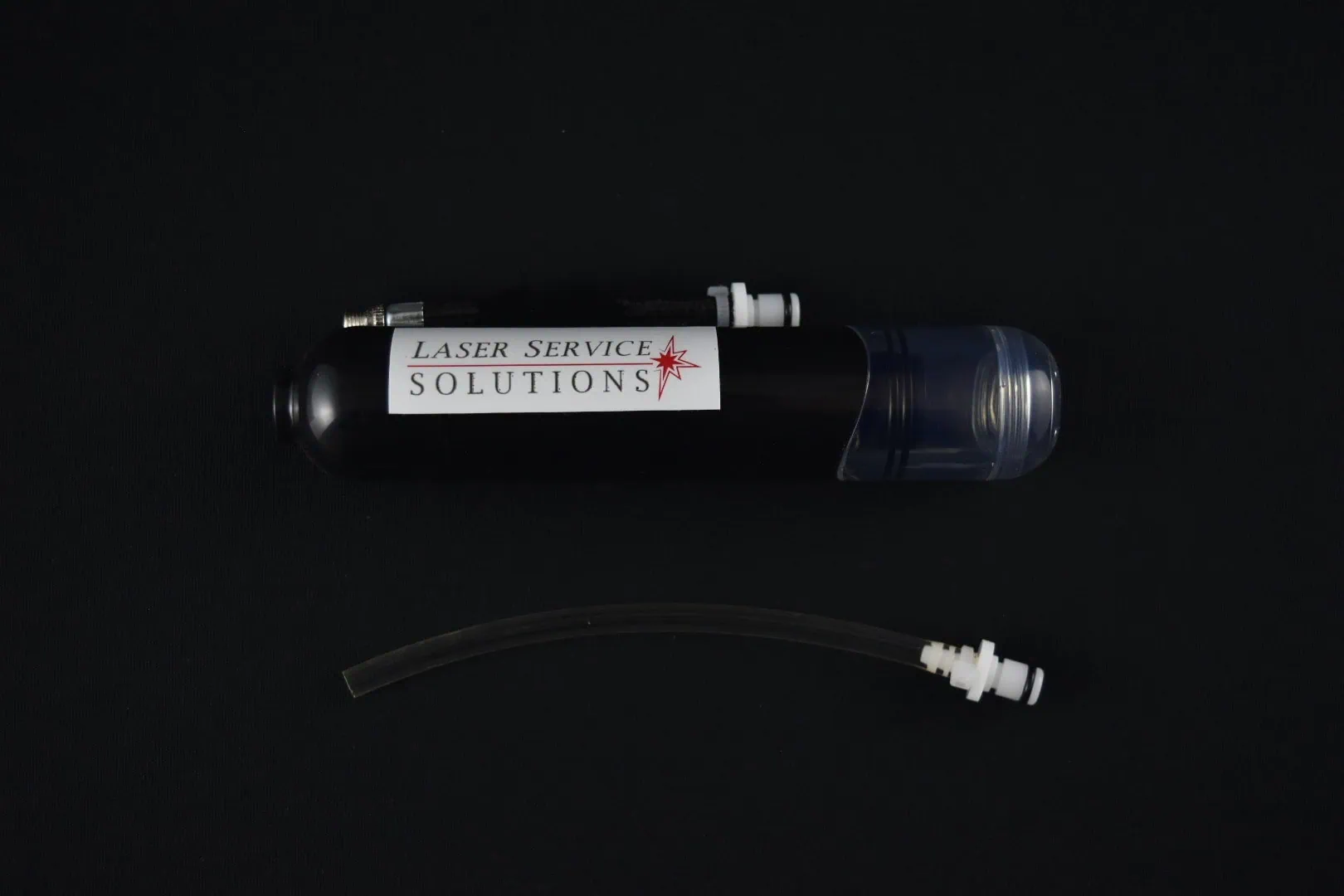 A Soprano Handpiece Drain Kit, consisting of a black cylindrical device labeled Laser Service Solutions with a clear cap, is displayed on a black background. Below it is a short, flexible tube with fittings on both ends.