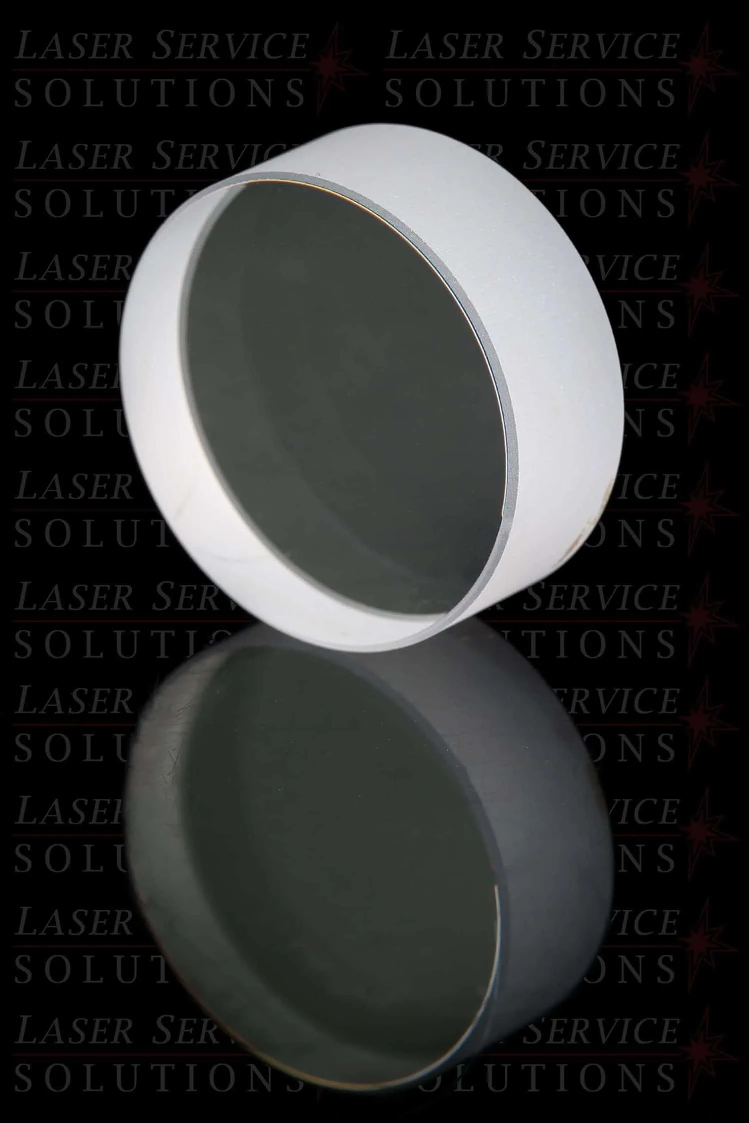 The Candela Gmax Pro Alex Turning Mirror, a round, flat, reflective optical lens with a white edge, is shown upright and mirrored on a glossy surface. The background features the repeated text “Laser Service Solutions.”.