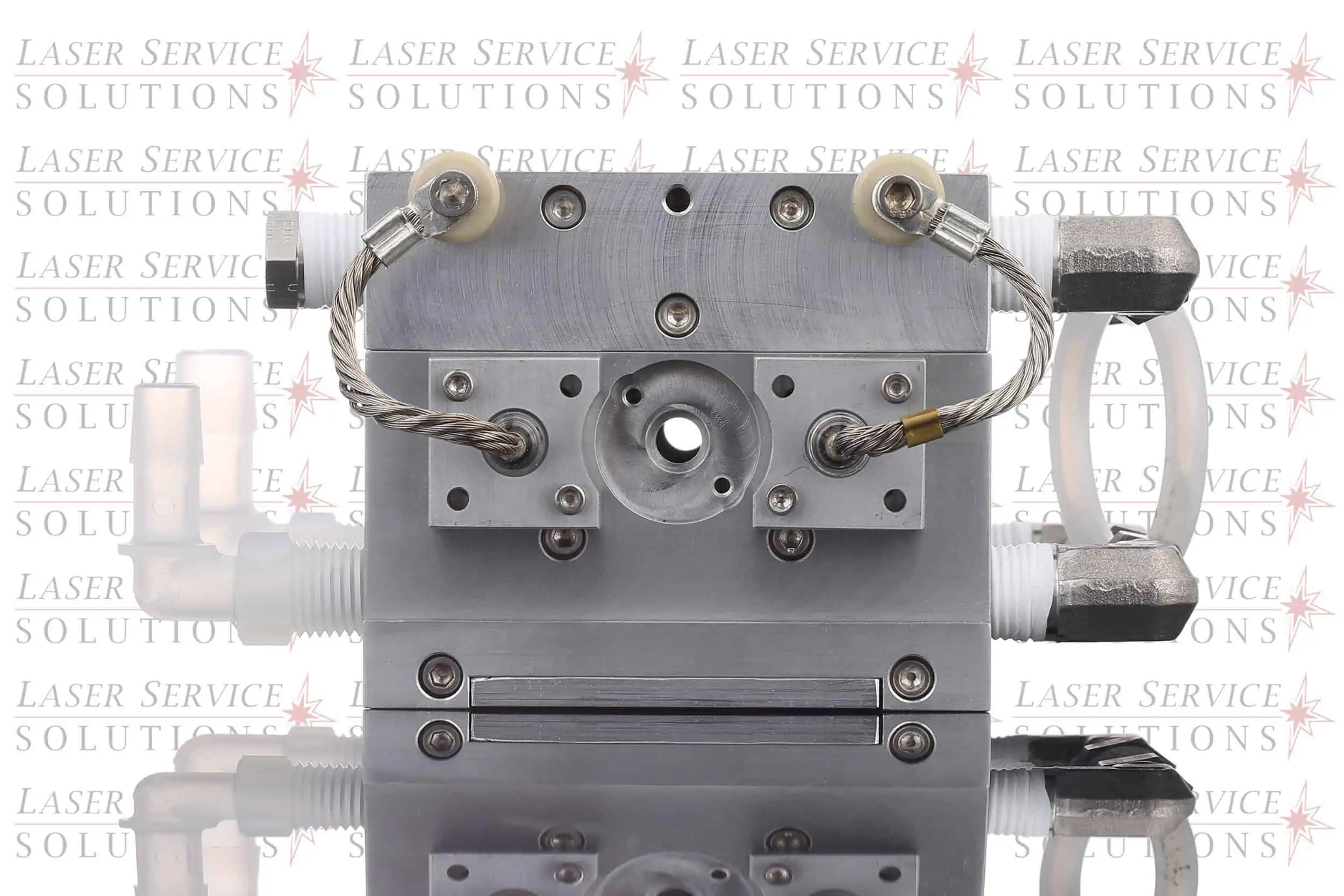 An Elite+ Yag Pump Chamber laser part with wires and fittings is shown, set against a background repeating Laser Service Solutions text. The chamber features ports, screws, and tubing connected on either side, with a reflective surface below.
