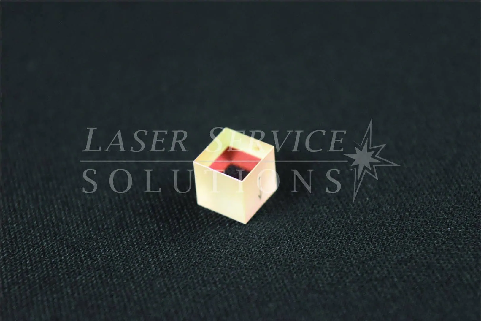 A Harmony KTP Crystal for 532nm Tip, featuring a small gold-colored design, rests on a black textured surface with the LASER SERVICE SOLUTIONS watermark across the image.