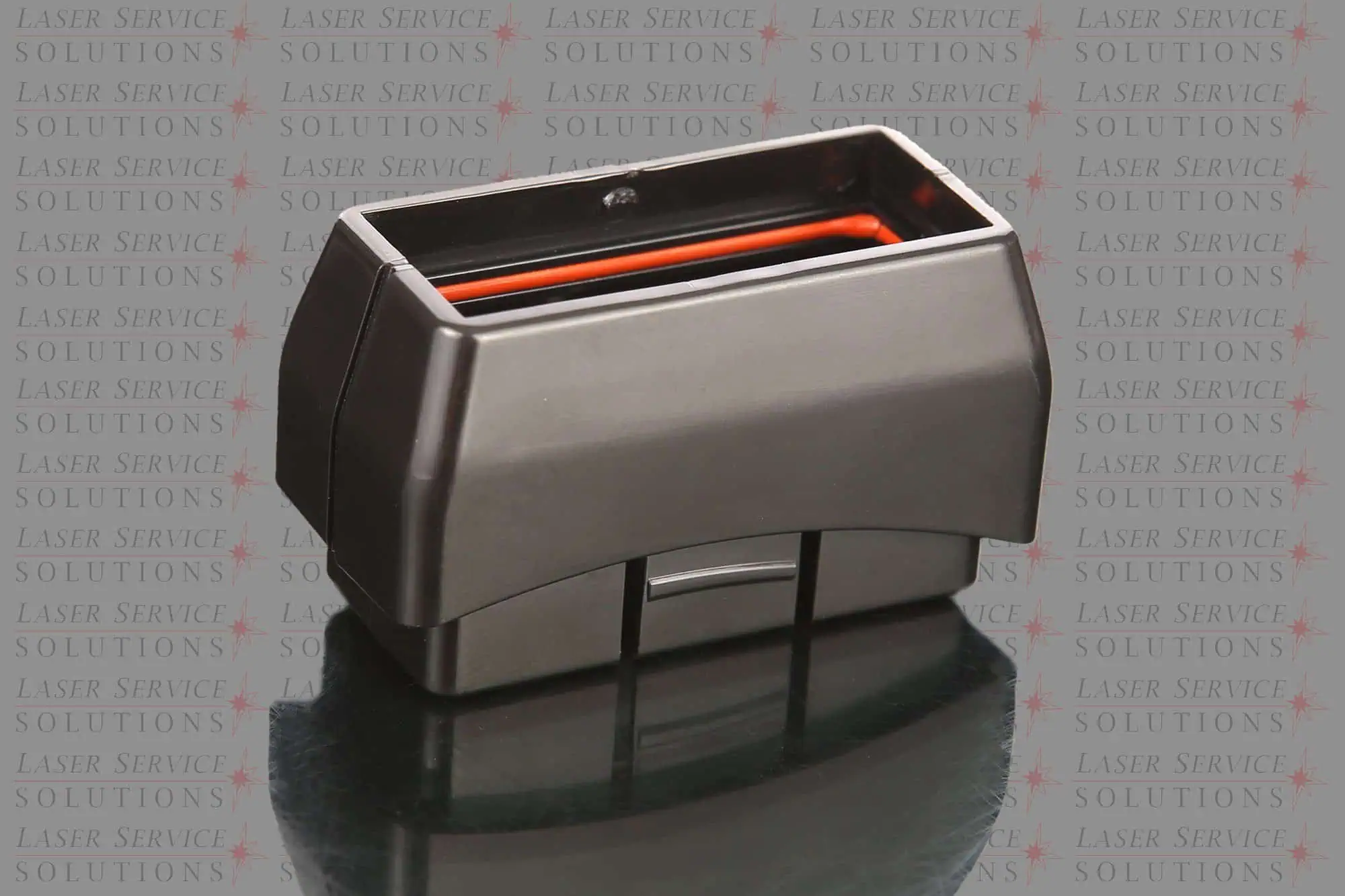A close-up of the Harmony Lightguide Cover, a rectangular black plastic component with a red inner lining, displayed on a reflective surface. The background features repeated Laser Service Solutions text.