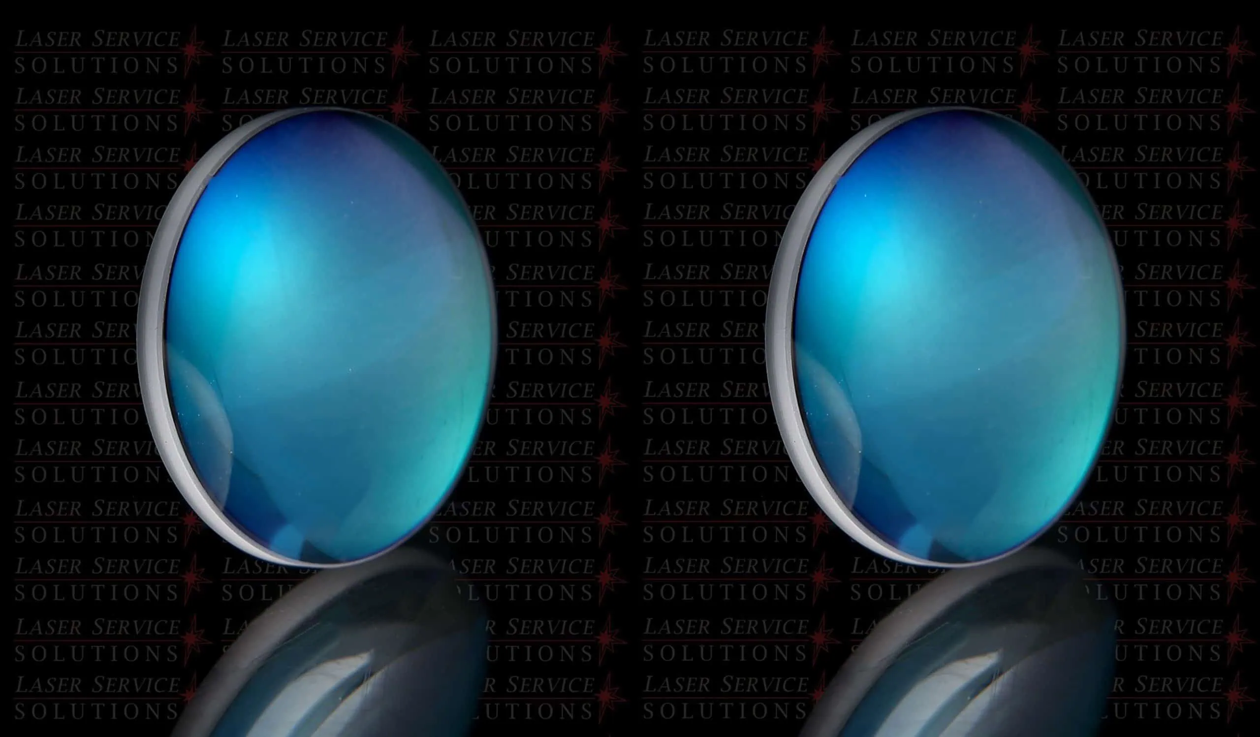 Two shiny blue Candela MGL Fiber Focusing Lenses are placed side by side on a reflective surface, with a dark background featuring the repeated text Laser Service Solutions in red and gray.