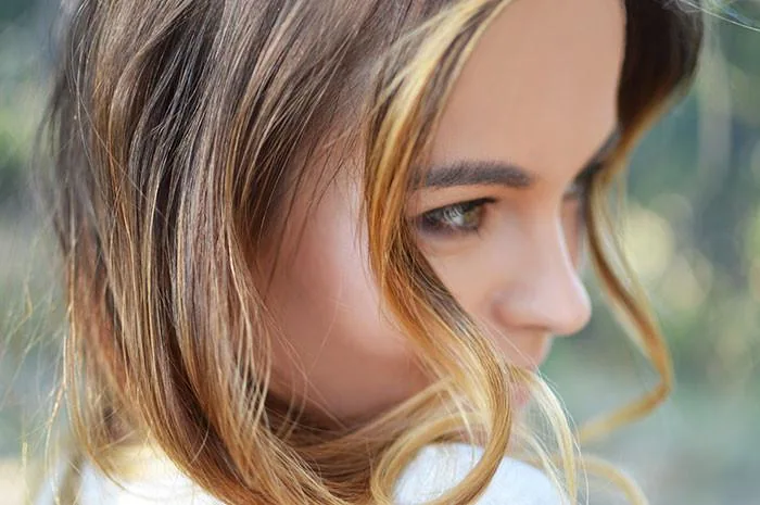 woman with blond hair looking over her shoulder